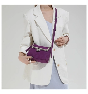Detailed shot of purple velvet shell bag with vintage metal clasp and leather strap