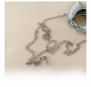 Detail of silver metallic purse featuring a polished chrome chain strap and textured leather