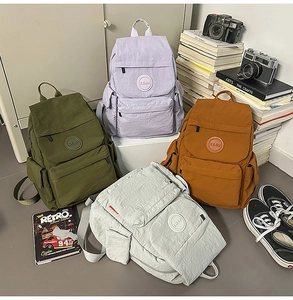 Détail de sacs à dos scolaires en nylon léger en olive, lilas, marron et gris sur plat