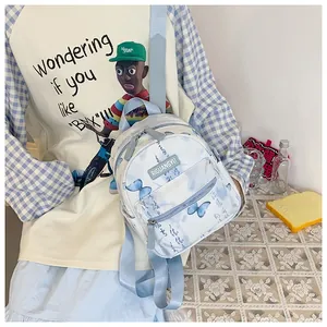 Close-up of white canvas mini backpack featuring blue butterfly prints and calligraphy