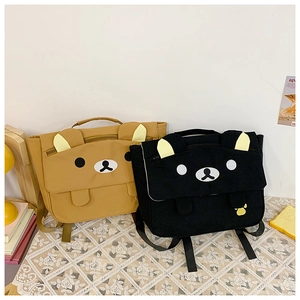 Detail view of cute bear face embroidery on canvas backpacks in brown and black