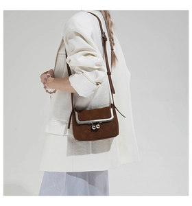 Detail view of a vintage brown suede crossbody bag with silver kiss-lock frame and chain strap