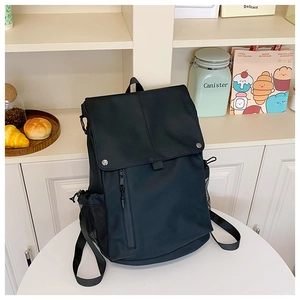 Detail of black backpack with flap cover, metal buckles, and vertical zipper pocket