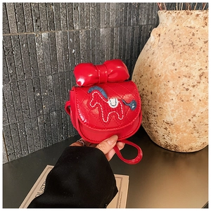Détail d'un sac à main rouge pour enfant en cuir matelassé avec nœud et motif poney