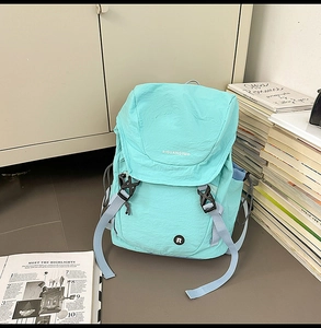 Detail eines hellblauen Nylon-Rucksacks mit Schnallenverschluss und Logo auf der Klappe
