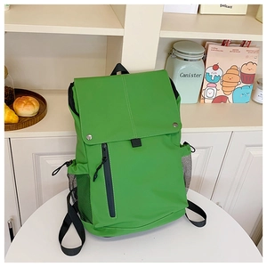 Detail of bright green backpack featuring a side mesh pocket and front vertical zip pocket