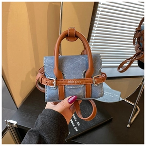 Gros plan détaillé d'un mini sac bandoulière en denim avec des brides en cuir marron et boucles