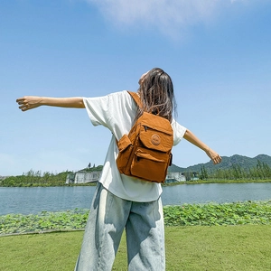 Sac à dos enfant marron caramel de grande capacité dans un parc ensoleillé au bord de l'eau