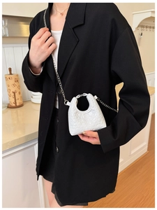 Detail of white heart-embossed mini bag with silver chain strap on black blazer