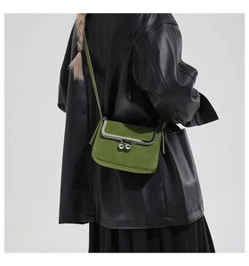 Detailed view of sage green faux suede crossbody bag with vintage metal kiss lock closure