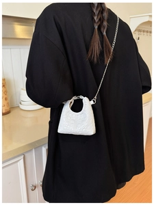 Close-up of mini white floral embossed kid bag with metal chain strap and top handle