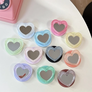 Flat lay of colorful heart-shaped phone grip mirrors with glitter resin frames