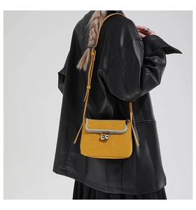 Detail of yellow leather crossbody bag with silver ball clasp on black leather jacket