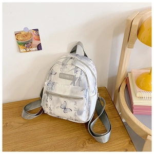 Detailed close-up of a mini backpack featuring grey butterfly prints and Chinese calligraphy