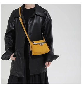 Detail of yellow matte crossbody bag with retro metal spherical clasp and thin shoulder strap