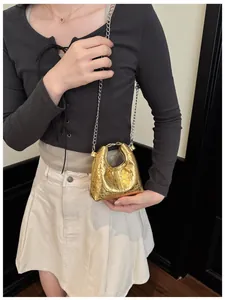 Detailed view of micro gold heart-quilted handbag with metallic finish and silver chain