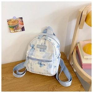 Detail view of a light blue canvas backpack with butterfly print in a cozy indoor setting