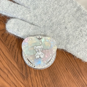 Détail du support de téléphone en cœur avec un ours argenté et bordure de strass