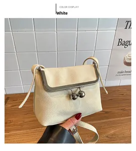 Detailed close-up of white lychee grain leather crossbody bag with metal frame clasp
