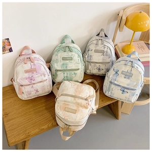Detailed view of canvas mini backpacks with butterfly prints on a wooden bench