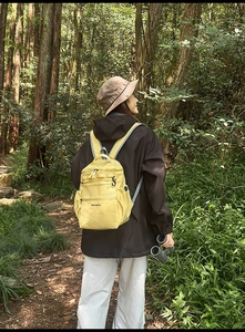Dettaglio dello zaino da trekking giallo in tessuto impermeabile in un bosco