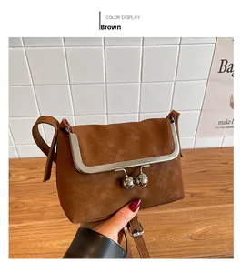Close-up of brown litchi pattern leather crossbody bag with vintage kiss-lock closure