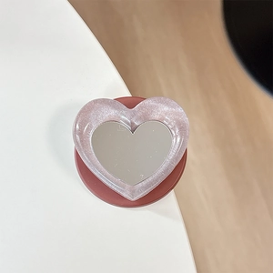 Macro shot of heart-shaped glitter phone grip with integrated makeup mirror surface