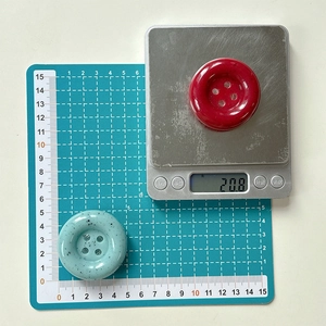 Détail du support de téléphone bouton moucheté montrant la taille sur un tapis vert