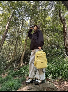 Zaino da trekking giallo acceso con tasche multiple mostrato in un ambiente forestale