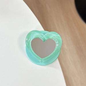 Detail of mint green heart-shaped phone grip with glitter resin and makeup mirror surface