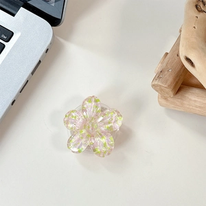 Detailed macro view of a 3D resin flower phone grip with colorful sequins on white desk