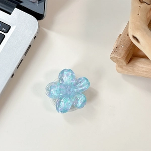 Close-up of translucent light blue floral phone socket with purple sequins on a desk
