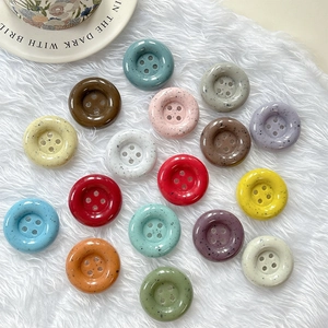 Vue à plat de boutons colorés en résine avec taches d'encre sur tissu blanc