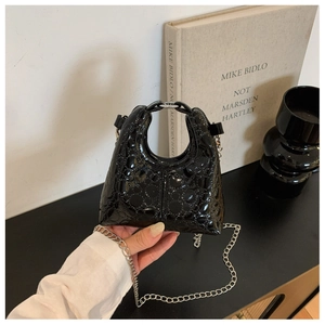 Close-up of black patent leather mini bag featuring embossed floral textures and silver chain
