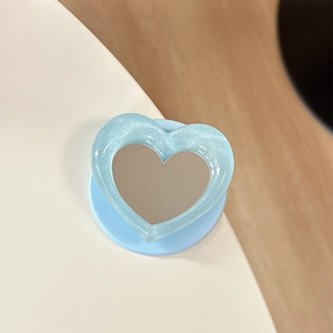 Macro shot of light blue heart-shaped phone grip with glitter frame and built-in vanity mirror
