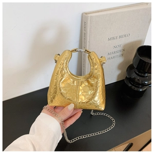 Detailed view of mini golden quilted handbag with silver chain and rounded top handle