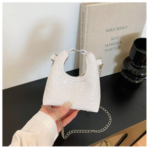 Detail of white heart-quilted mini bag with round silver handle and chain strap