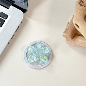 Macro shot of 3D light blue sequin flower phone grip on a white desktop background