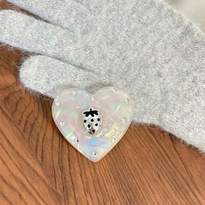 Vue détaillée d'accessoire cœur nacré avec strass et petit motif de fraise en métal