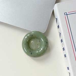 Détail du support de téléphone motif marbre vert à éclaboussures sur un bureau minimaliste