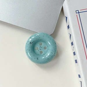 Gros plan d'un support de téléphone bouton bleu à taches d'encre sur fond blanc