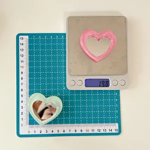 Detail shot of heart-shaped glitter phone grips in pink and green with size and weight scale