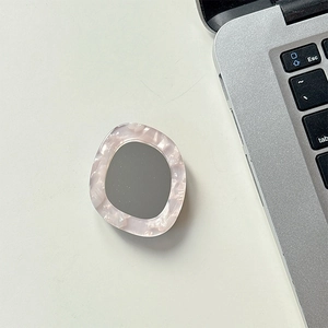 Detail of dolphin mirror phone grip with pink marble texture on office desk