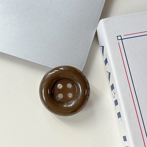 Détail d'un bouton marron foncé à quatre trous avec texture mouchetée et finition résine polie