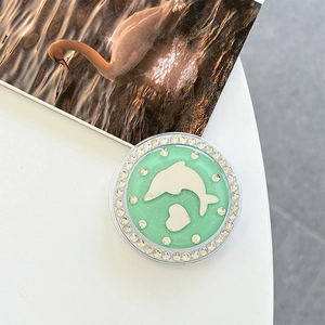 Close-up of a mint green phone grip with rhinestones, silver dolphin, and heart patterns