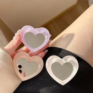 Close-up of heart-shaped resin phone grips with built-in mirrors in three pastel colors