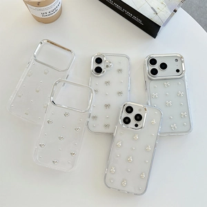 Clear iPhone case with silver 3D bow, crown, and heart motifs on white background
