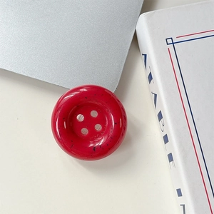 Vue rapprochée d'un support de téléphone bouton rouge avec taches d'encre noire et fini poli