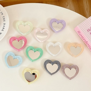 Flat lay of colorful glitter heart-shaped phone grips with integrated makeup mirrors