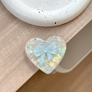 Macro detail of heart-shaped magnetic phone grip with rhinestone border and blue bow
